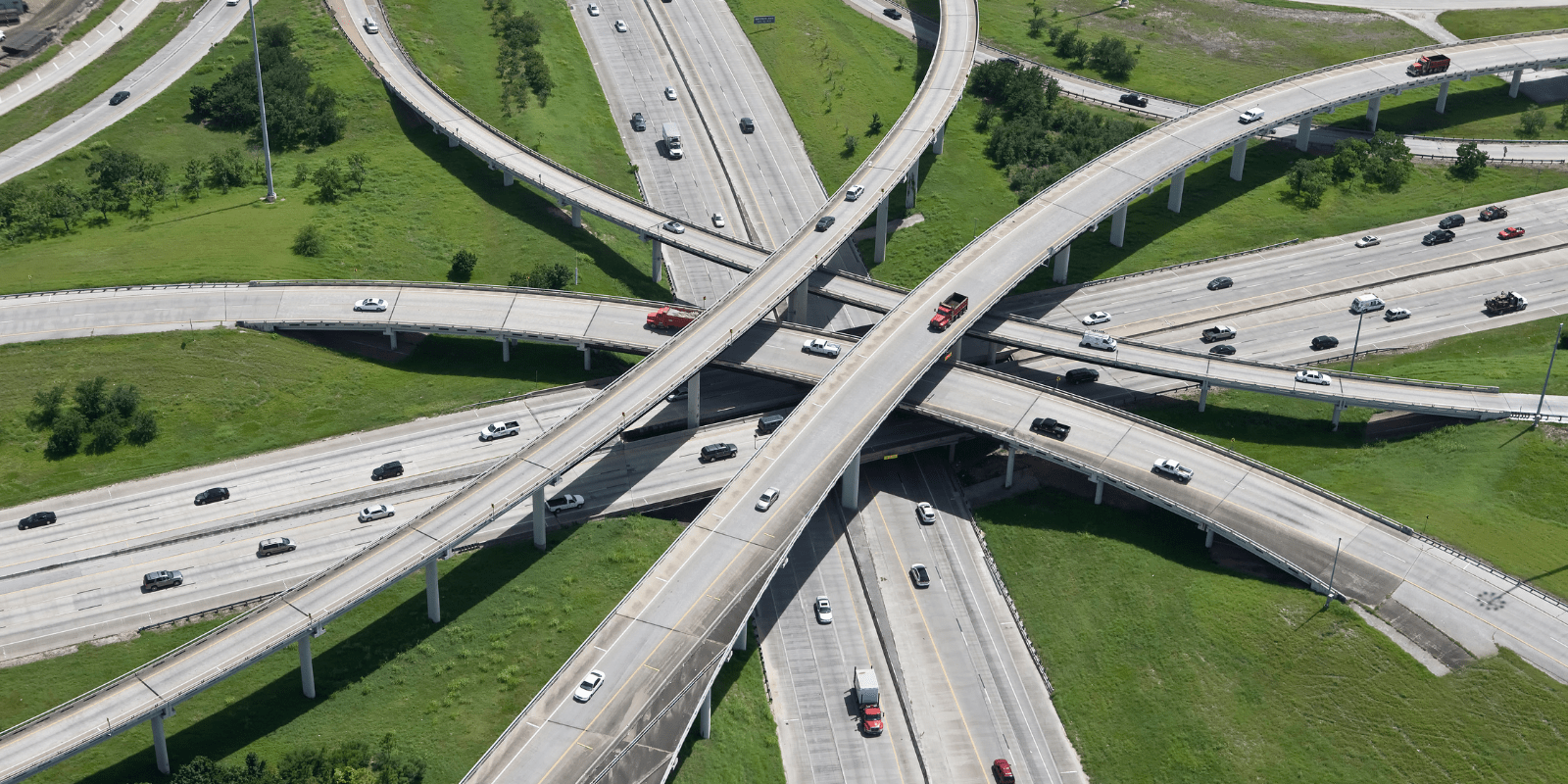 Luftaufnahme einer Autobahnkreuzung mit fließendem Verkehr und grünem Umfeld